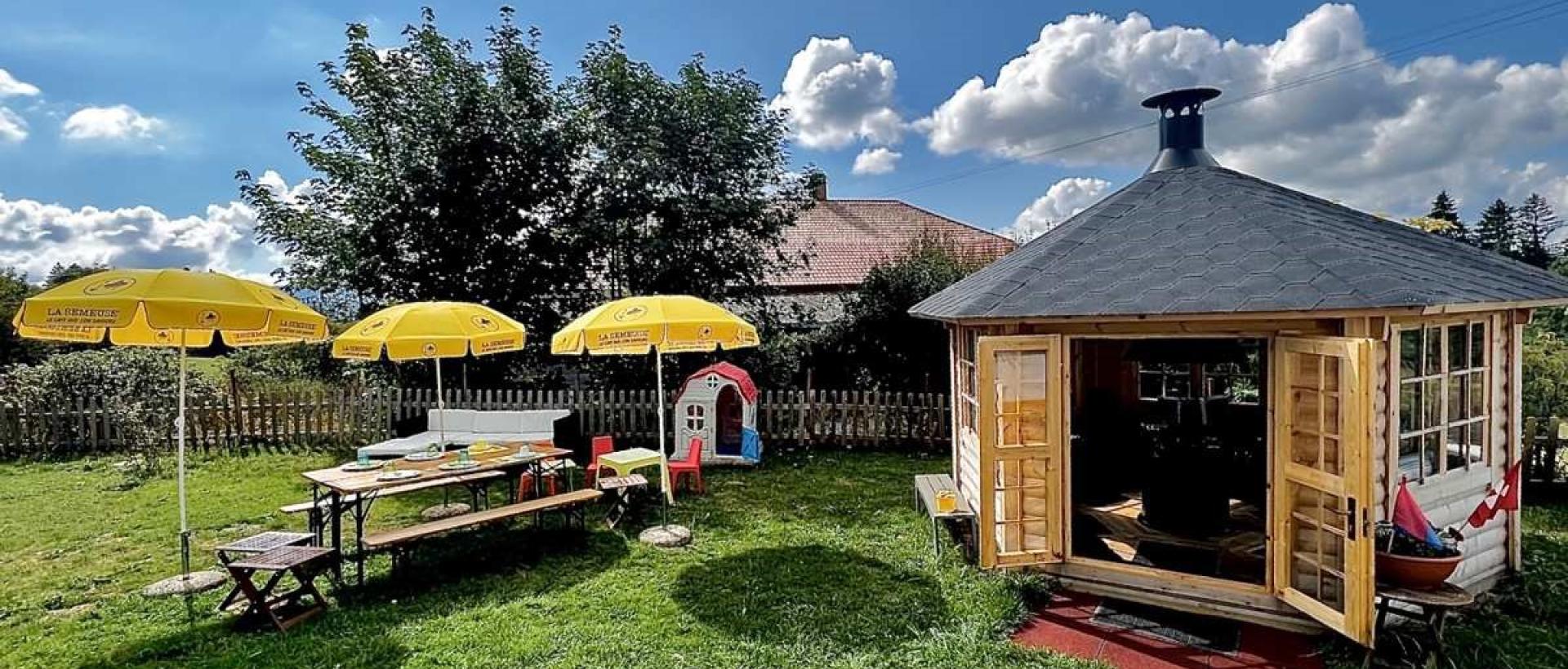 Cabane barbecue en été extérieur tables et parasol Restaurant Val de Travers Jura suisse