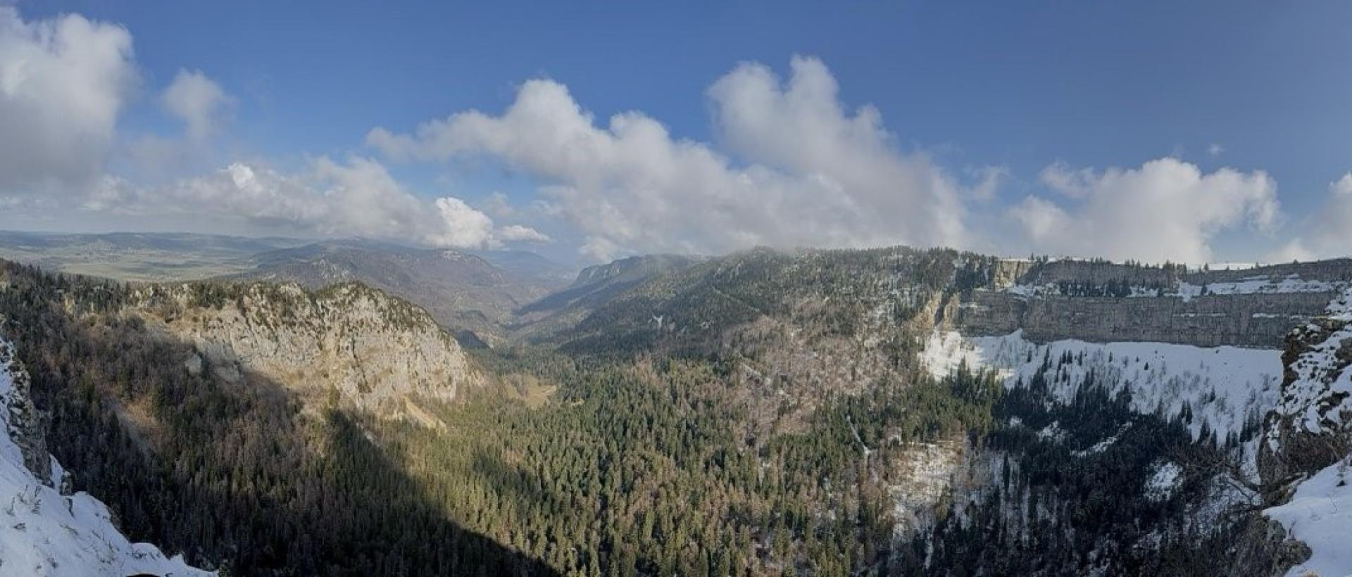 Vue panoramique du Creux du Van en hiver avec paysage enneigé et falaise spectaculaires