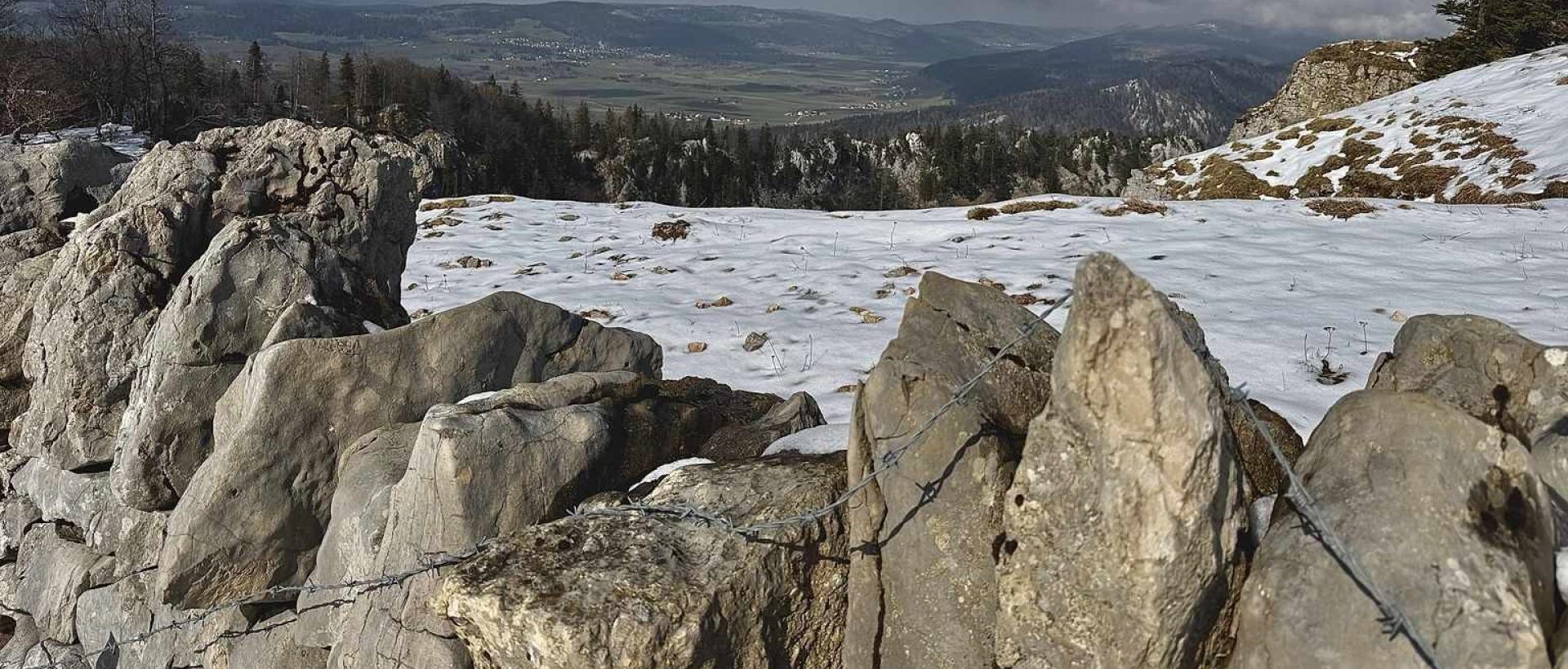 Creux du Van en hiver avec mur de pierres et paysage enneigé dans le Jura suisse