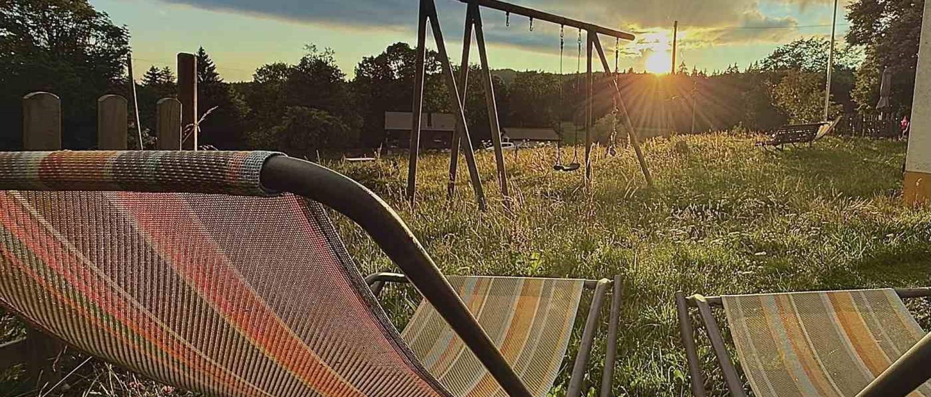 Terrasse et transats au coucher de soleil à l'Hôtel Les Cernets Val de Travers