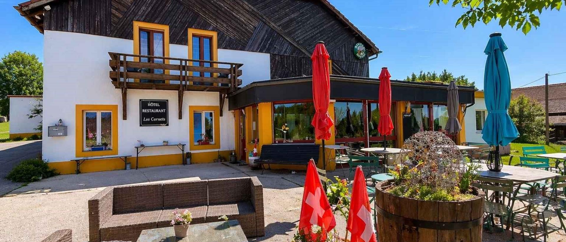 Terrasse extérieure de l'Hôtel Restaurant Les Cernets dans le Val-de-Travers, Jura suisse, avec espace détente et environnement nature