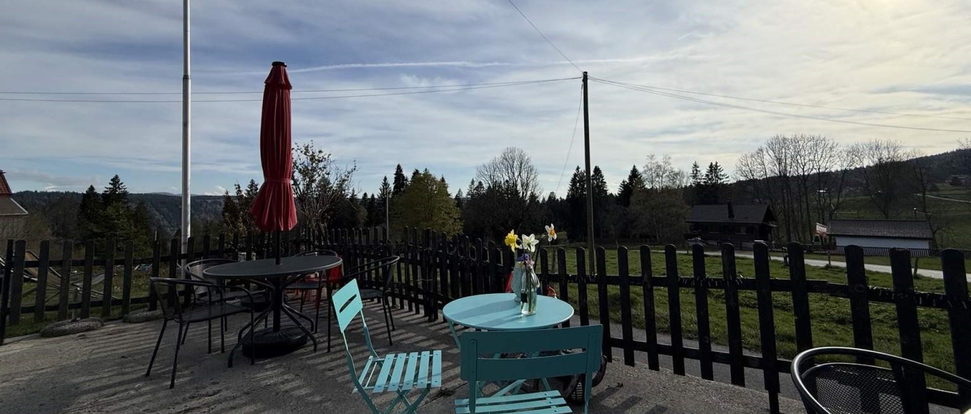 Terrasse avec drapeau Suisse et vue sur les paysages du Val de Travers Jura neuchâtelois