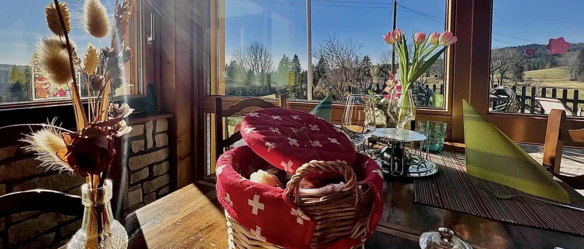 Table dressée au Restaurant Les Cernets avec vue sur le Val-de-Travers dans le Jura neuchâtelois
