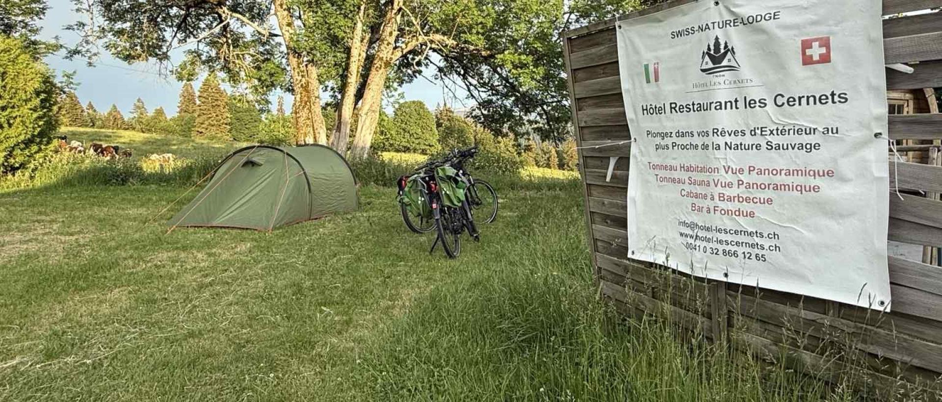 Espace Bivouac et halte cyclotourisme aux Cernets dans le Jura suisse, avec tente et vélo au coeur de la nature du Val de Travers