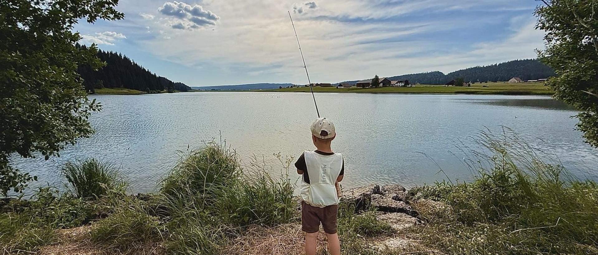 Lac des Taillères en fin de journée, un enfant pêche avec un panorama exceptionnel  dans le Val-de-Travers proche de l'Hôtel Les Cernets