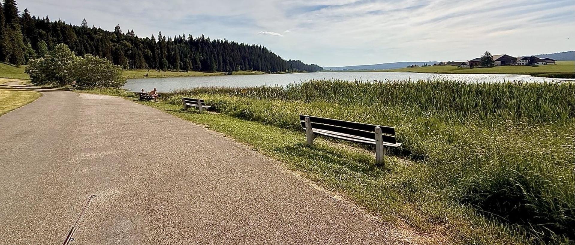 Panoramique du lac des taillères avec des bancs pour contempler la nature sauvage des lieux dans la vallée de la Brévine