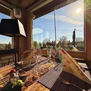Table du restaurant Hôtel Les Cernets avec vue panoramique sur le Val-de-Travers et le Jura suisse depuis l'intérieur