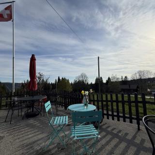 Terrasse avec drapeau Suisse et vue sur les paysages du Val de Travers Jura neuchâtelois
