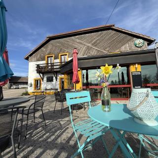 Terrasse ensoleillée de l'Hôtel Restaurant Les Cernets dans le Jura suisse avec tables et vue sur la campagne