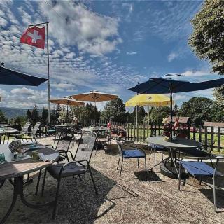 Terrasse et drapeau Suisse flottant à l'Hôtel Restaurant Les Cernets au Val-de-Travers