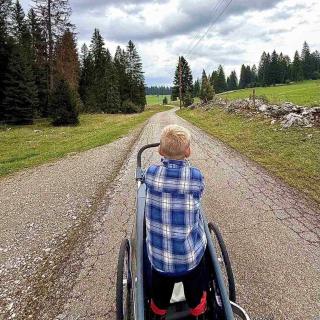 Enfant sur une remorque de vélo découverte des prairies du Jura neuchâtelois