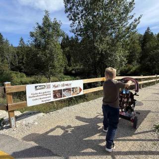 Enfant avec une poussette à l'entrée des Mines d'Asphalte lors d'une sortie familiale au Val de Travers