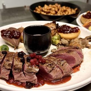 Assiette avec une selle de chevreuil poêlés, sauce aux airelles, pommes et poires en garnitures, choux de Bruxelles, marrons glacés, cèpes de bordeaux aux lardons